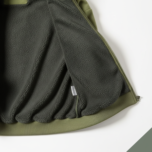 Close-up of the ultra-soft, charcoal fleece lining inside a deep forest green FROVIK Outdoor Fleece Jacket, highlighting its 